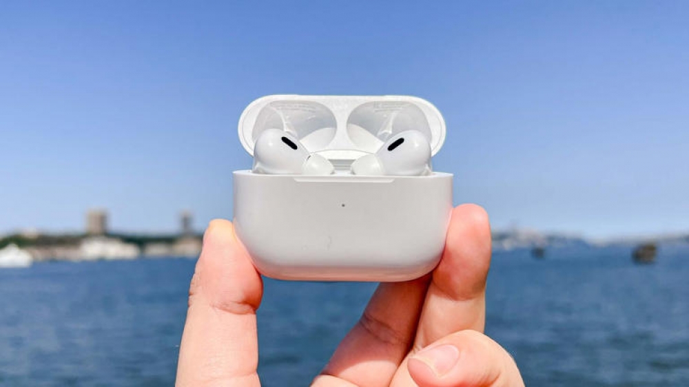 Apple AirPods being held in a mans hand