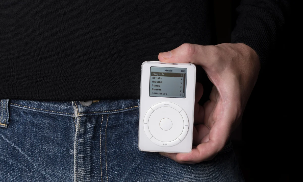 The original iPod, released in 2001. Held by Steve Jobs in his classic jeans and black turtleneck attire.