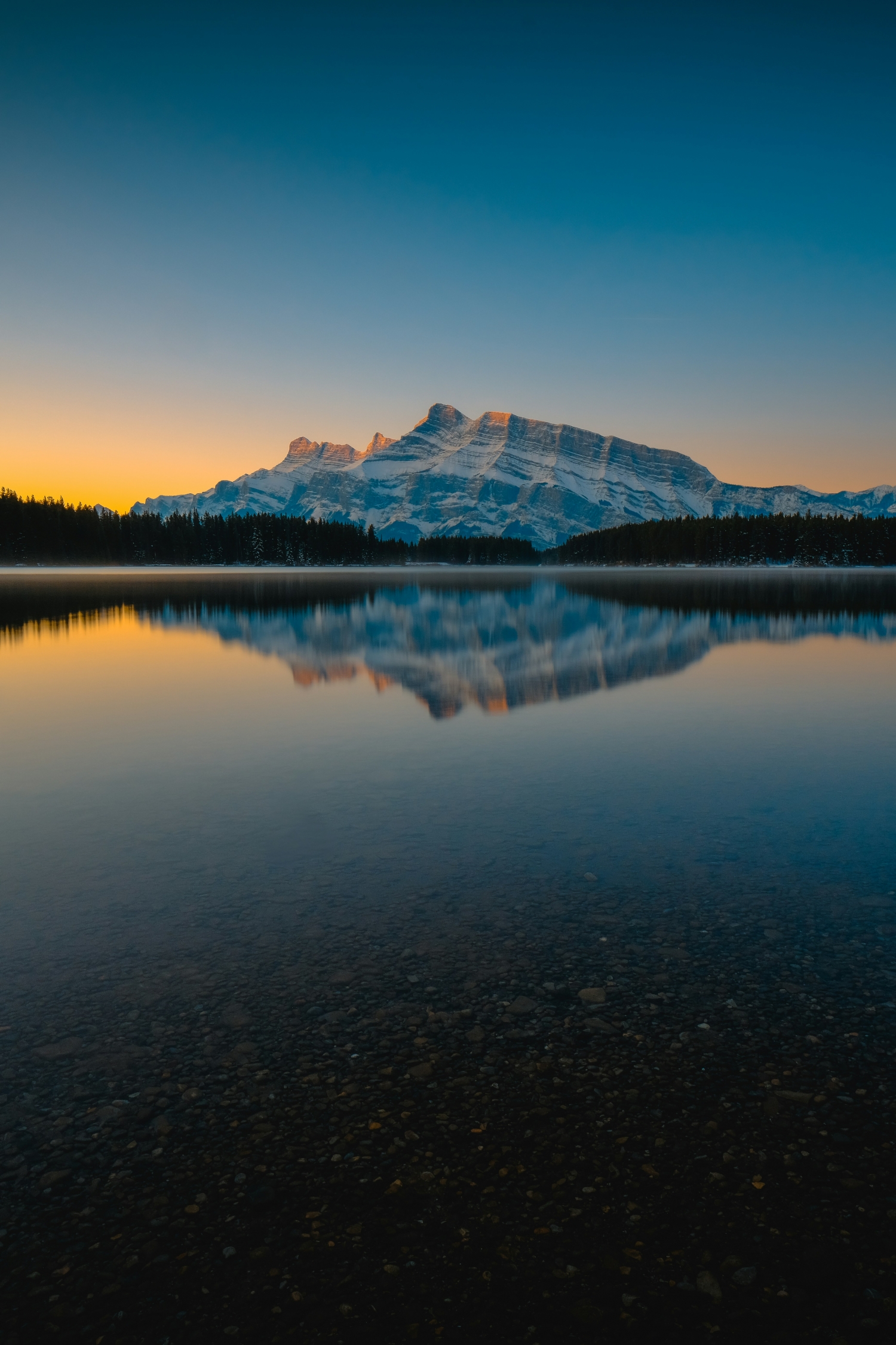 A Soft Orange Sunset Hits A Snowcapped Mountain