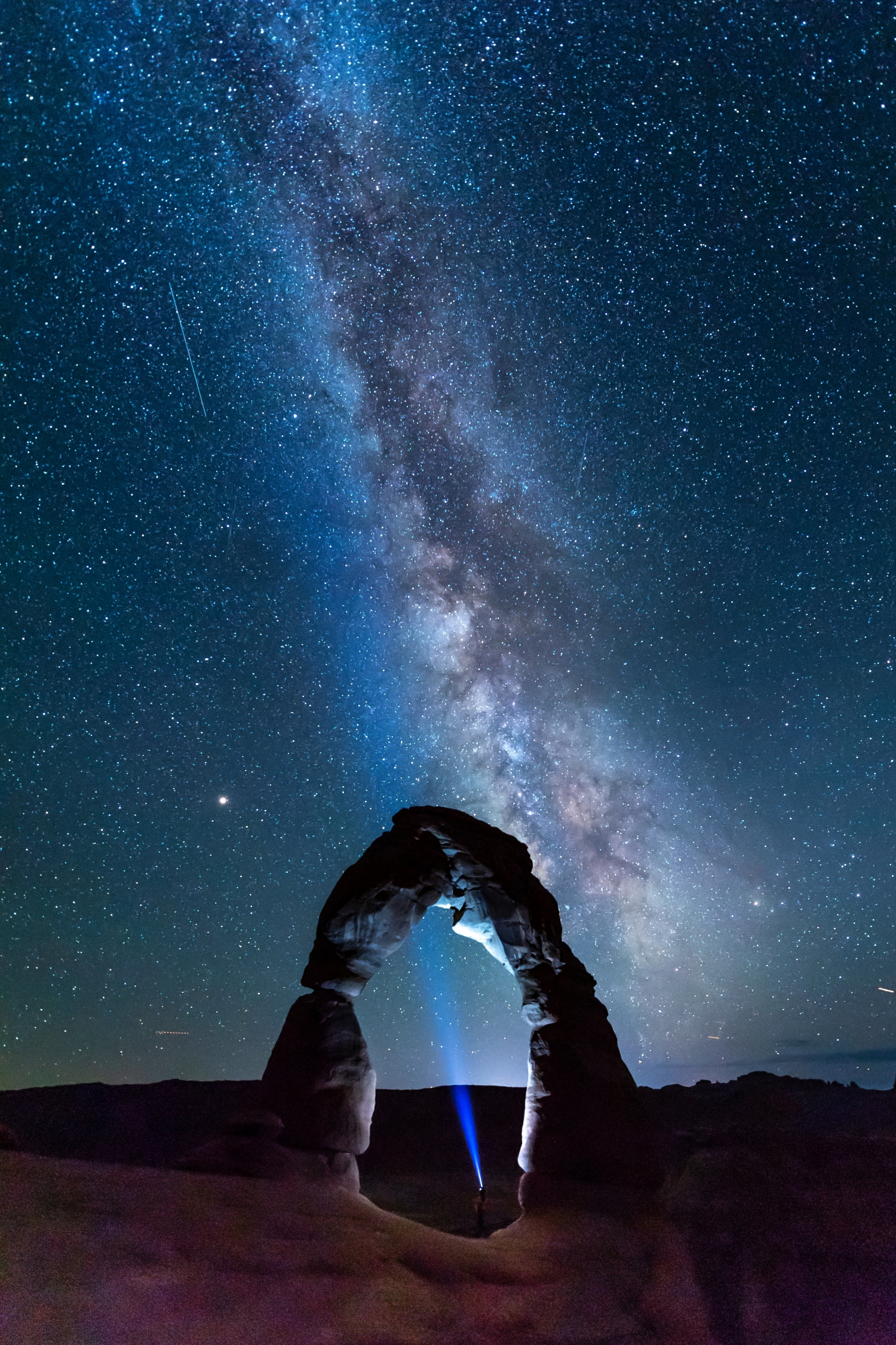 Arched Rock Formation In The Desert With Stars And Cosmos Clearly Visible Torch Light