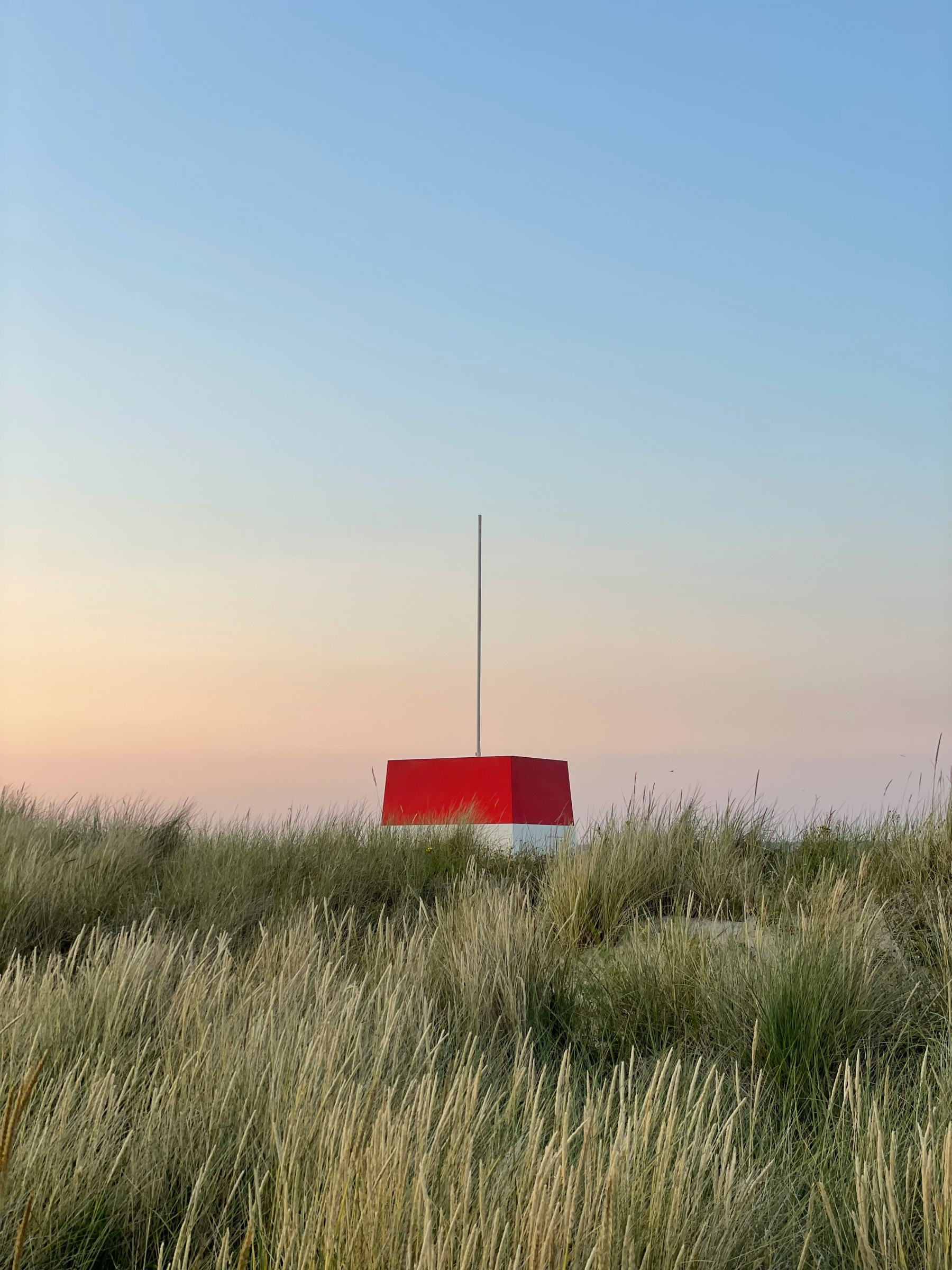 Red And White Structure In The Middle Of A Grass Field Sunset