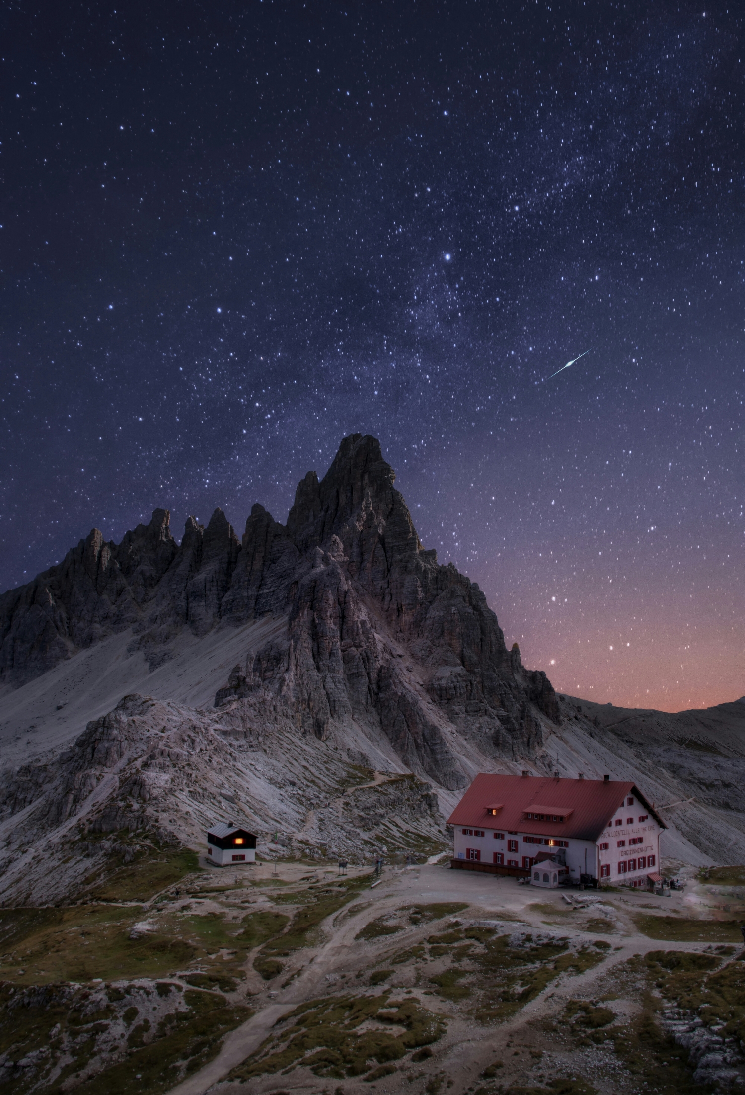 Stars With Shooting Star Above A Small Travel Lodge Next To A Mountain