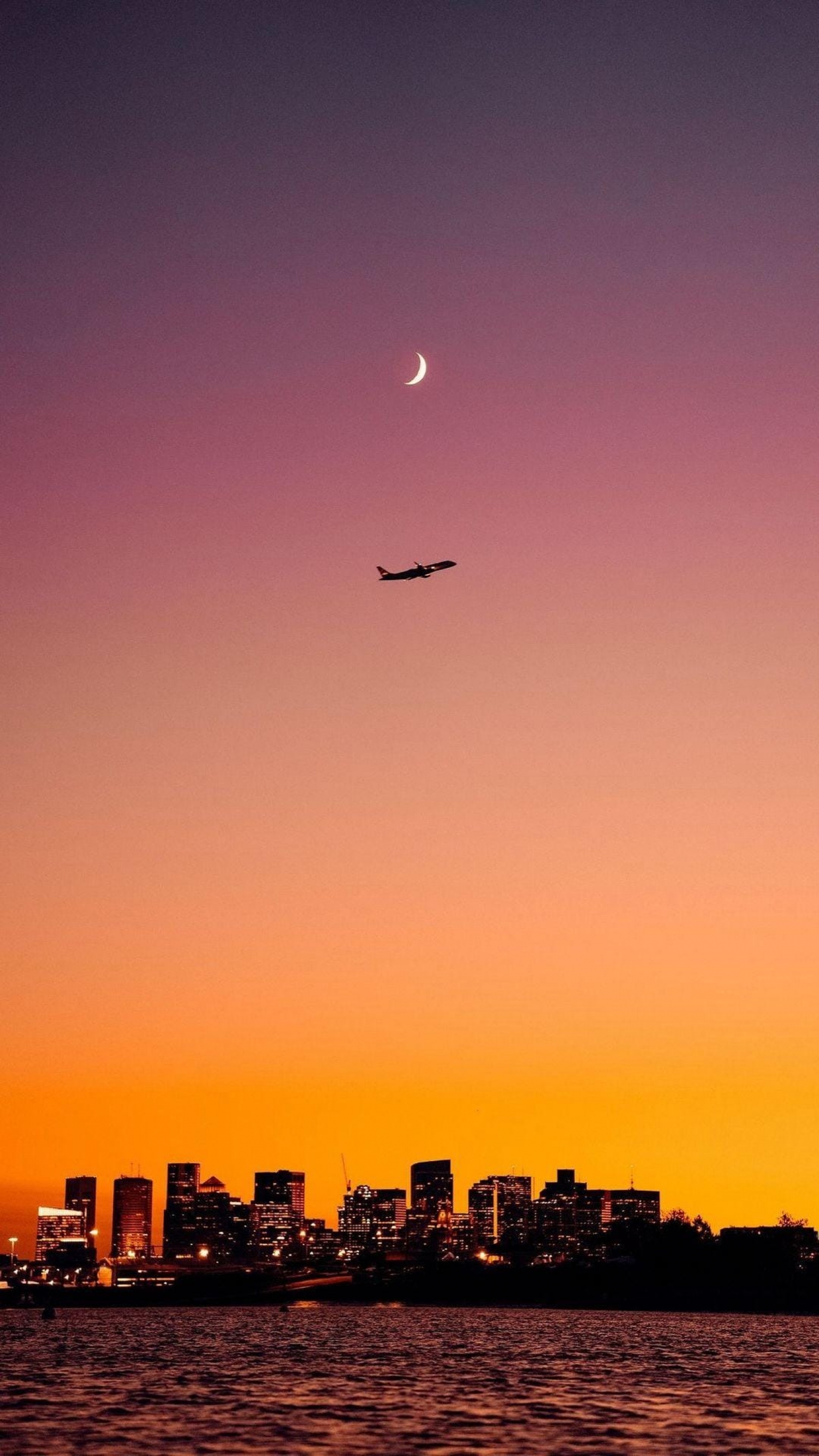 Sunset Over The City Skyscrapers With Plane And Moon In The Sky