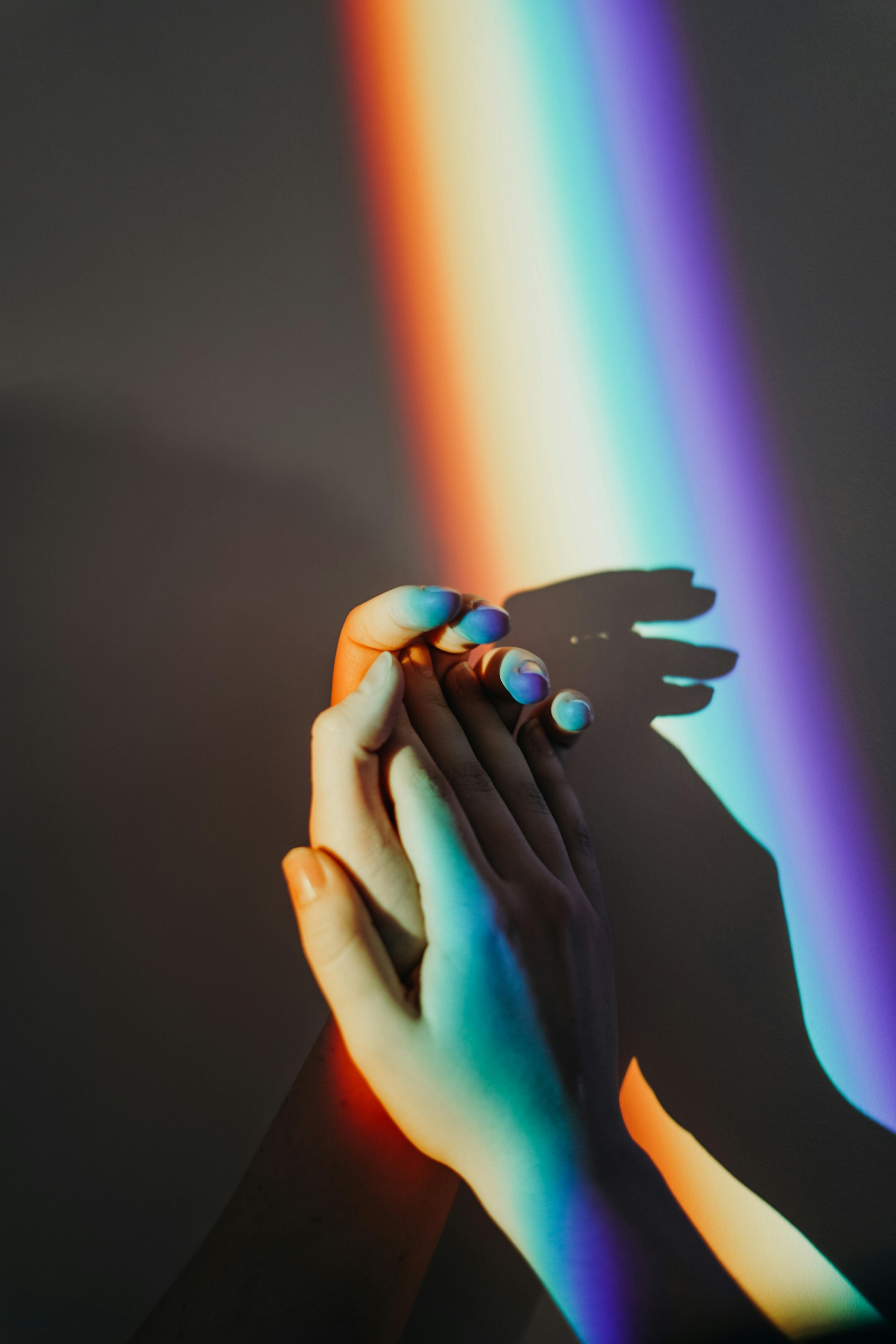 Two Lovers Hold Hands In A Strip Of Rainbow Light