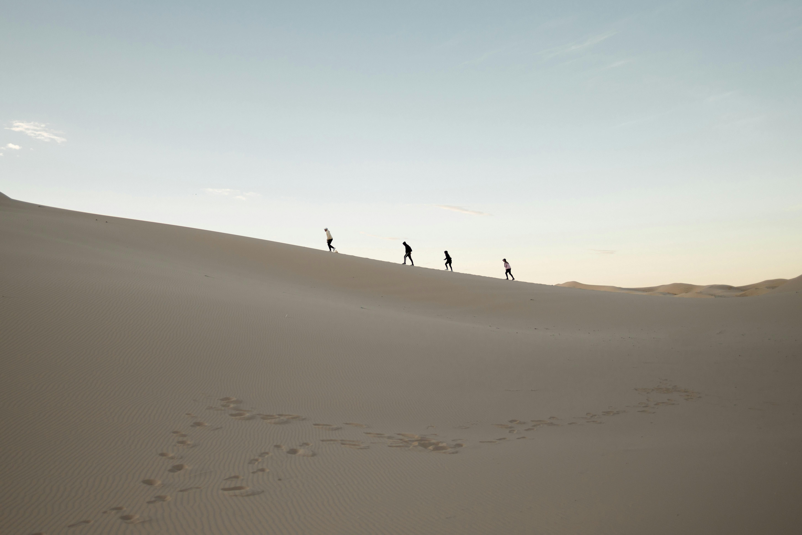 Four Men On A Sand Dune In The Desert wallpaper for Apple iPhone, Apple Watch, Mac, iPad and Apple Watch