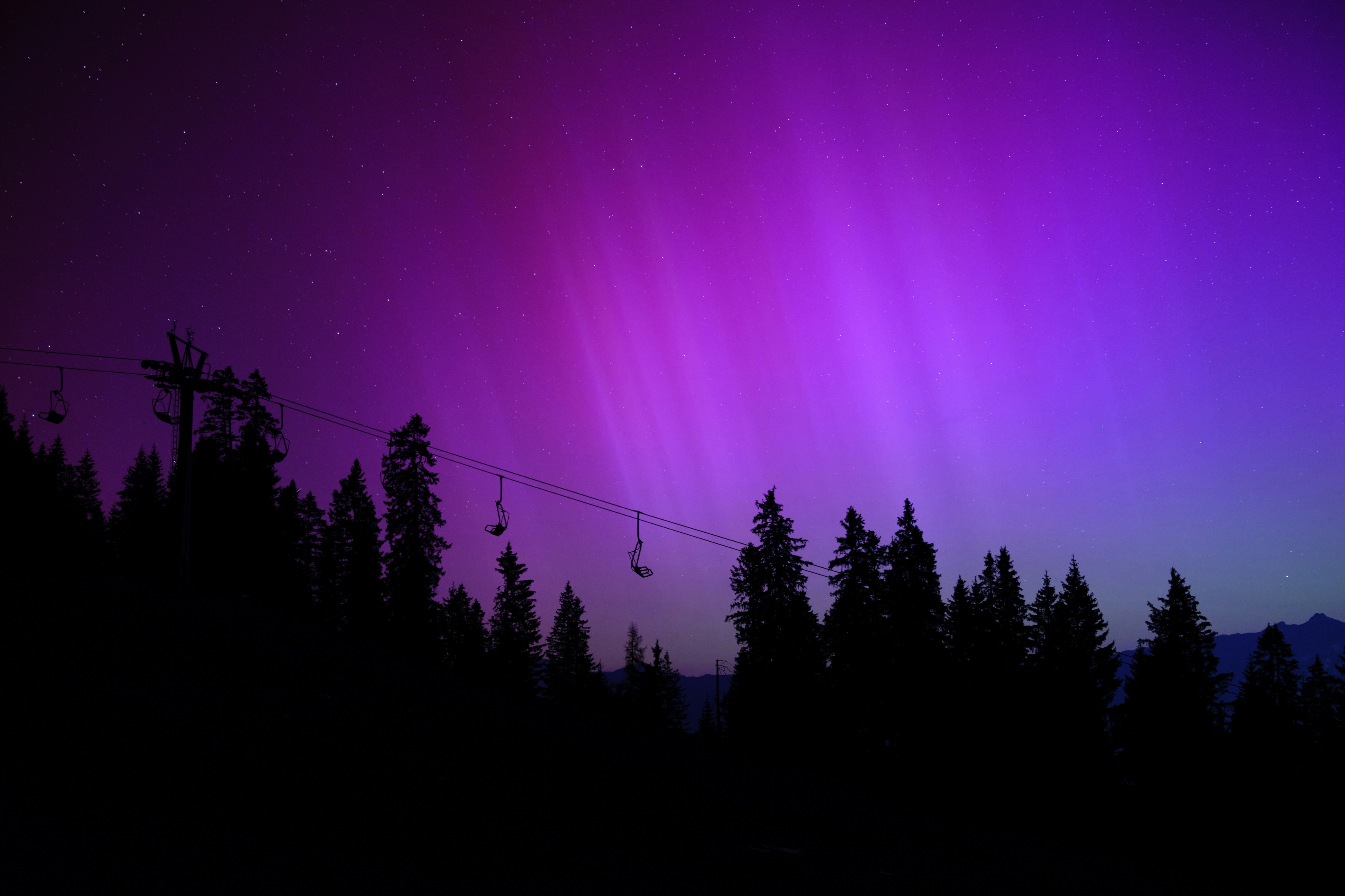 Purple Aurora Borealis Over Forest With Ski Lifts High Res