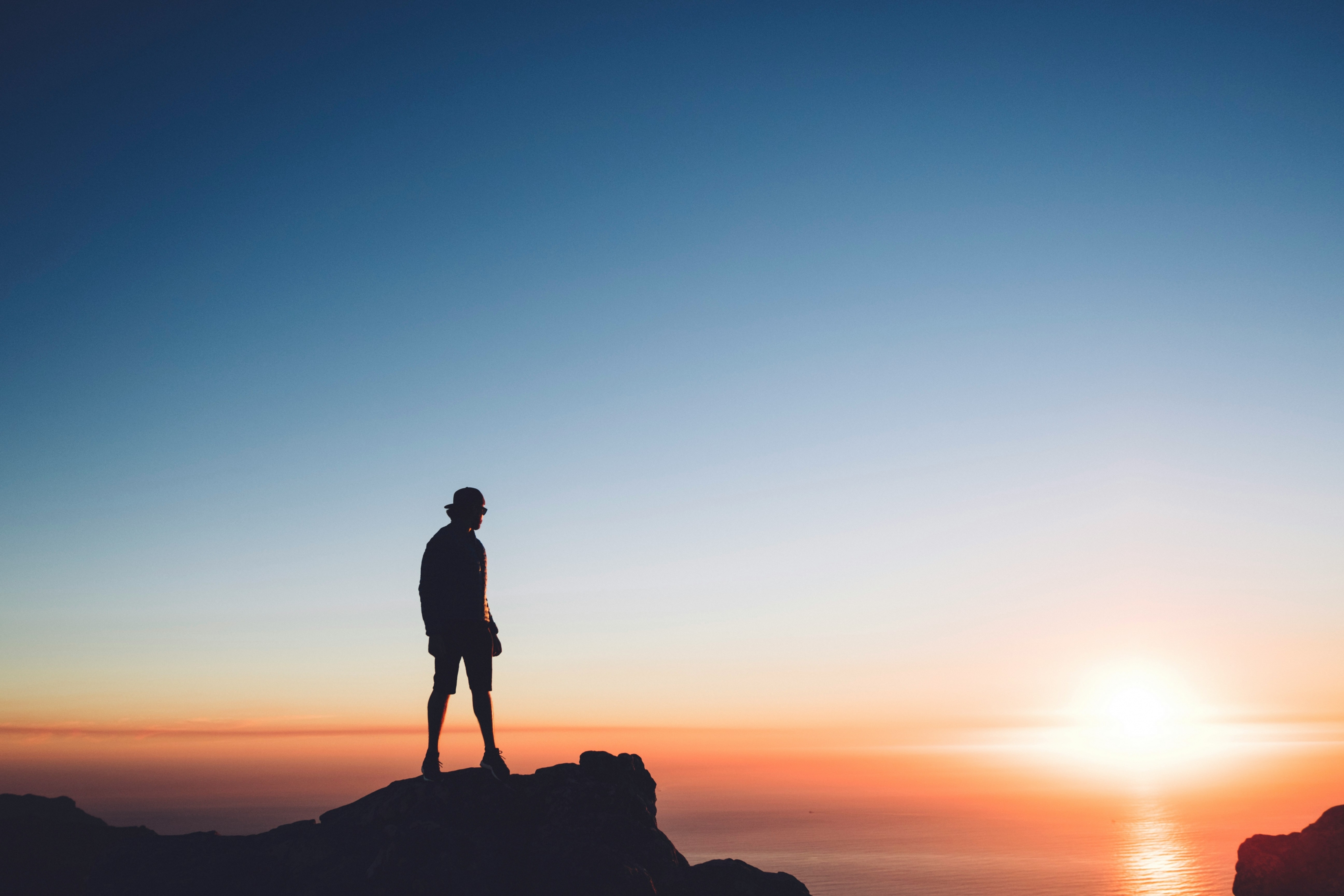 Silhouette Of A Man On The Edge Of A Cliff At Sunset 5K wallpaper for Apple iPhone, Apple Watch, Mac, iPad and Apple Watch